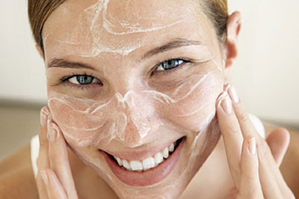 Smiling Young Woman Applying Face Cream --- Image by © Royalty-Free/Corbis